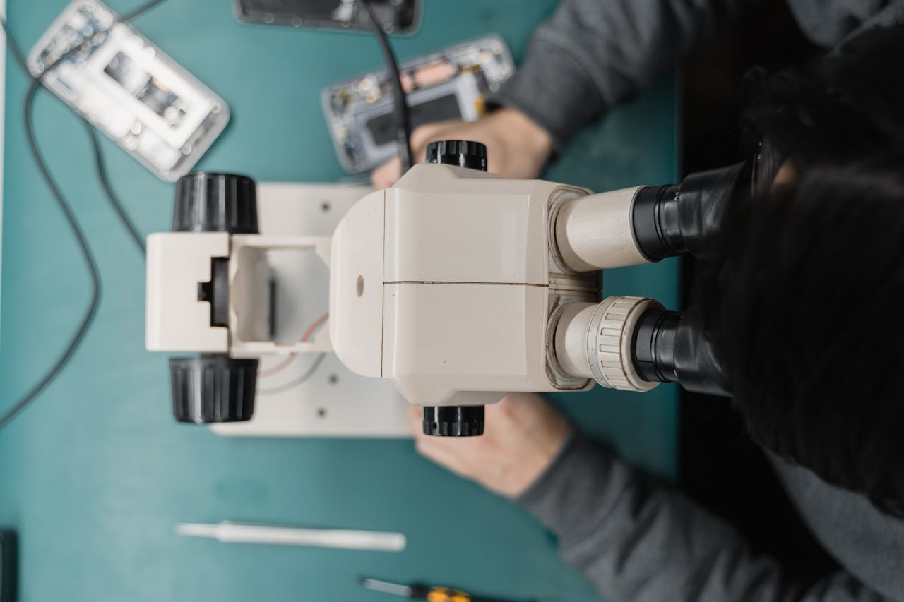 Home Close-up of a technician using a microscope for phone repair, highlighting precision work.