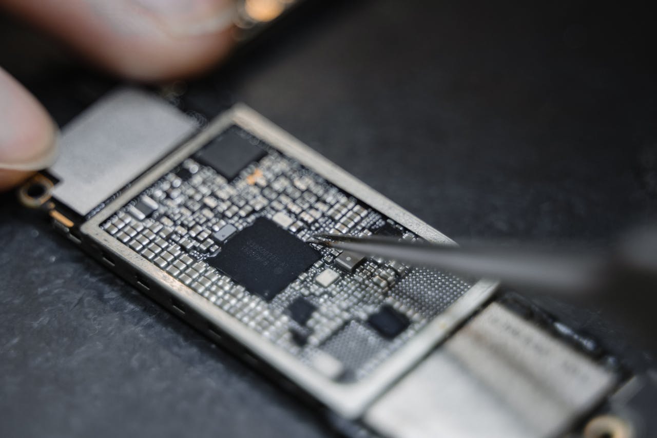 Home Detailed view of a technician using tweezers to fix an electronic circuit board.